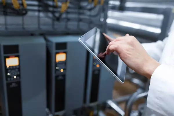 Technologist with grey tablet setting up production line in dairy factory